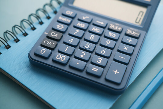 Close up of blue calculator and notepad on color background 