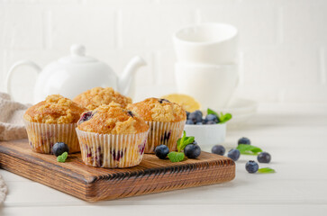 Lemon muffins with blueberries and shtreisel with fresh berries on a white wooden background. Delicious breakfast. Copy space.