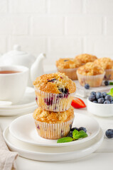 Lemon muffins with blueberries and shtreisel with fresh berries on a white wooden background. Delicious breakfast. Copy space.