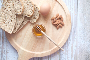 Top view of fresh honey , bread , egg and almond nut on table 