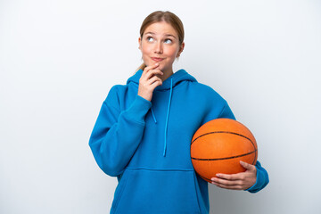 Young caucasian woman playing basketball isolated on white background looking up while smiling