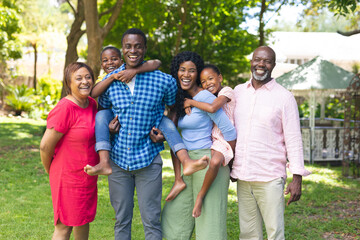 Portrait of happy african american multi-generational family standing together in backyard