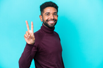 Fototapeta premium Young Brazilian man isolated on blue background smiling and showing victory sign