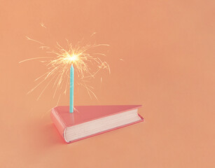 Coral-pink book in the shape of a cake slice with a sprinkler on an isolated pastel orange...