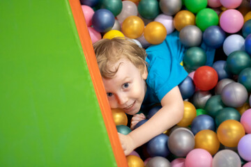 Fototapeta na wymiar Cute four year old blond child playing colorful balls, top view.