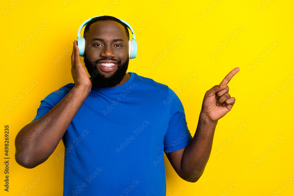 Poster Portrait of attractive cheerful guy listening hit demonstrating copy space isolated over bright yellow color background