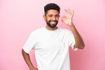 Fototapeta premium Young Brazilian man isolated on pink background showing ok sign with fingers
