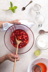 Woman preparing strawberry jam in her kitchen at home, top view