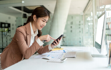 Asian woman using smart phone and laptop in office.