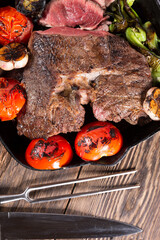 A piece of meat grilled in a cast-iron pan with vegetables