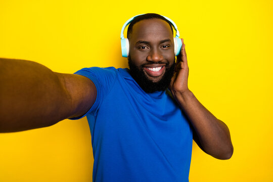 Self-portrait of attractive cheerful guy listening melody enjoying stereo free time isolated over bright yellow color background