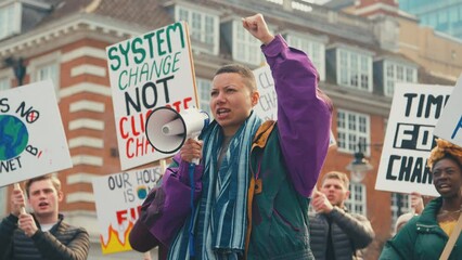 Group of protestors using megaphone holding placards and chanting slogans on demonstration march to promote awareness of climate change - shot in slow motion