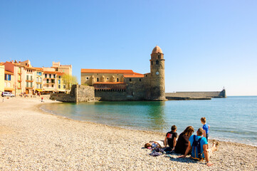  Collioure, France. Family (unrecognizable people, back view) relaxing on the beach during Easter holidays. Picturesque Collioure is popular tourist travel destination.