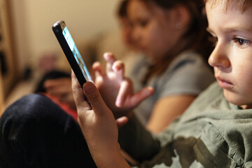 Close up of a line of small group of kids using mobile phones at home. Group of children sitting in...