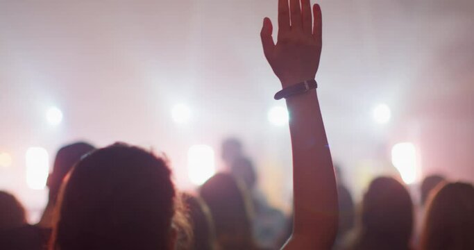 Hands of Female Christian Worshiping and Praising God while Singing on Christian Festival Concert. People with Raised Hands on Music Live Event with Lights. 4K back view handheld shot in slow motion