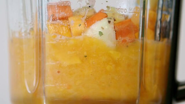 Chopped vegetables pumpkin, potatoes, carrots are full of vitamins are crushed in a glass bowl blender. Cooking puree soup and baby food.