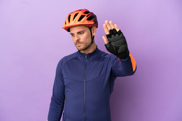 Young Brazilian cyclist man isolated on purple background making stop gesture and disappointed - obrazy, fototapety, plakaty