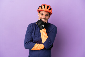 Young Brazilian cyclist man isolated on purple background happy and smiling - obrazy, fototapety, plakaty