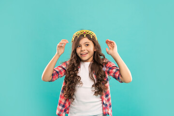 laughing kid with curly hair in princess crown on blue background, beauty