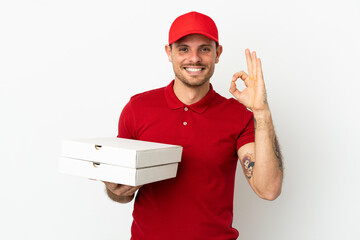 pizza delivery man with work uniform picking up pizza boxes over isolated  white wall showing ok...