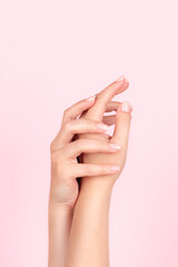 Female hands with beautiful natural manicure - pink nude nails on pink background. Nail care concept