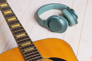view of guitar and green headphones on wooden background, closeup
