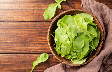 Fresh arugula leaves in brown bowl top view