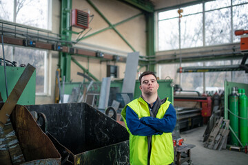 Young man with Down syndrome working in industrial factory, social integration concept.