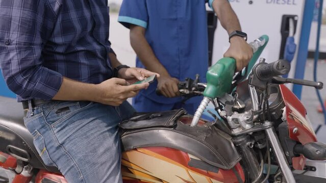 Customer busy using mobile phone while refuling petrol at gas station - concept of safety, danger of using mobile at filling station and smart phone addiction.
