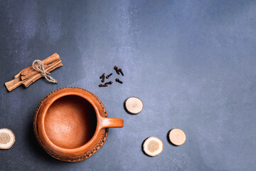 Red clay mug on a saucer. Top view, location at the bottom left in the corner. Cinnamon, cloves and...