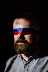 Man with Russian flag blindfold on black background, Russian propaganda closed people's eyes concept.