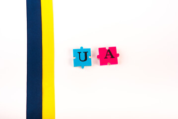 Colorful blue-yellow fabric ribbon and puzzles of letters Ukraine isolated on white. The symbol of...