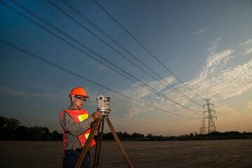 Engineer or surveyor working with theodolite  equipment at a field have high voltage in background...