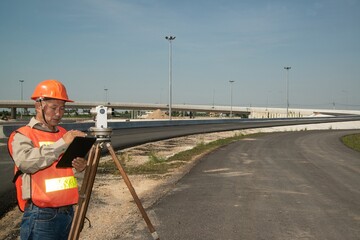 Fototapeta na wymiar Engineer or surveyor working with theodolite equipment at road construction site.
