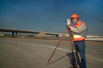 Engineer or surveyor working with theodolite  equipment at road construction site.