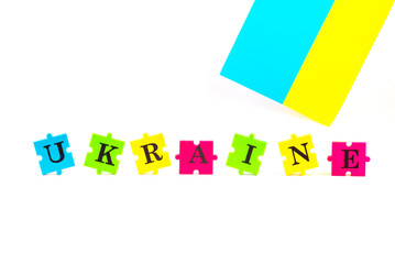 The word Ukraine, laid out from multi-colored puzzles of English letters and flag of Ukraine on a white background