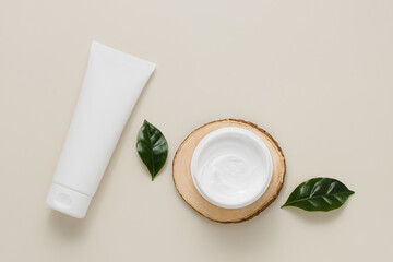 White mockup unbranded squeeze tube and cream bottle on wooden stand with leaves top view, eco...