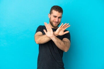 Naklejka premium Young handsome caucasian man isolated on blue background nervous stretching hands to the front