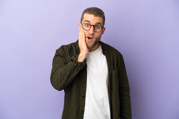 Young handsome caucasian man isolated on purple background with surprise and shocked facial expression