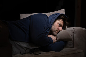 Senior Mann mit Migräne oder Depressionen hat sich einsam im dunkeln auf seine Couch zurück...