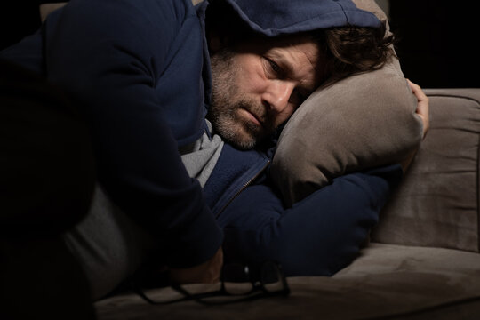 Senior Mann mit Migräne oder Depressionen hat sich einsam im dunkeln auf seine Couch zurück gezogen.