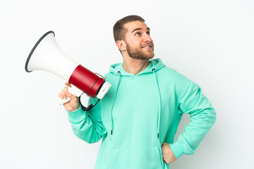 Young handsome caucasian man isolated on white background holding a megaphone and thinking