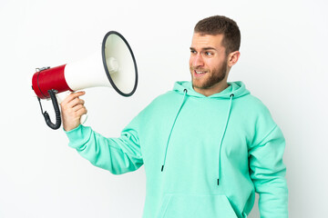 Young handsome caucasian man isolated on white background holding a megaphone with stressed expression