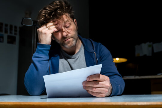 Ein Mann mit Sorgen hat einen unangenehmen Brief in der Hand, eine unbezahlbare Mahnung oder K&uuml;ndigung.