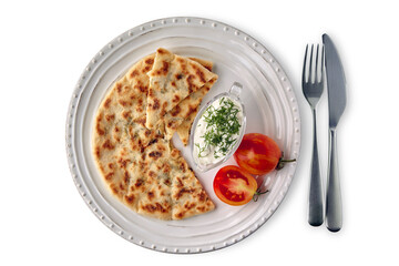 Flatbread with cheese and herbs and yoghurt sauce on a white plate