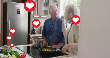 Animation of social media heart icons over senior couple cooking in kitchen - Powered by Adobe