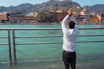 isolated young man prying the holy ganges river at river bank from flat angle