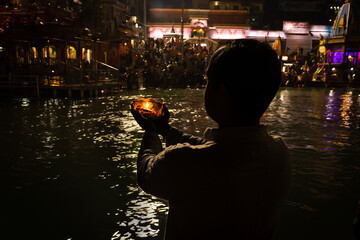 isolated young man prying the holy ganges river at river bank from flat angle
