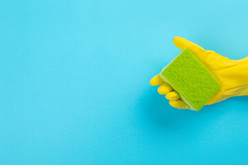 worker's hand in yellow rubber protective glove with micro fiber green sponge or washcloth. A maid or housewife takes care of the house. general or regular cleaning. 