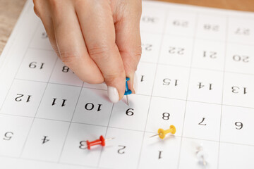 Blue Hand pin stuck on the day of the month in the calendar, business concept. beautiful female hand fingers